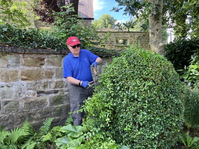 Volunteer trimming bushes in the Memorial Garden